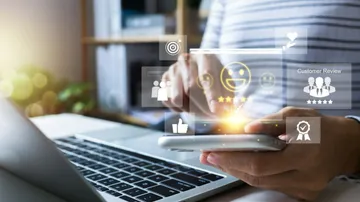 Jemand benutzt ein Handy mit eingeblendeten Symbolen für Bewertungen und Likes.