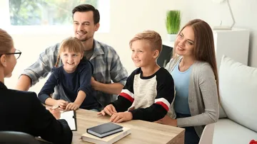 Eine Familie redet mit einer Beraterin am Tisch.