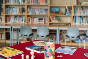 Bücherei mit Büchern und Spielfiguren auf einem Tisch und in Regalen